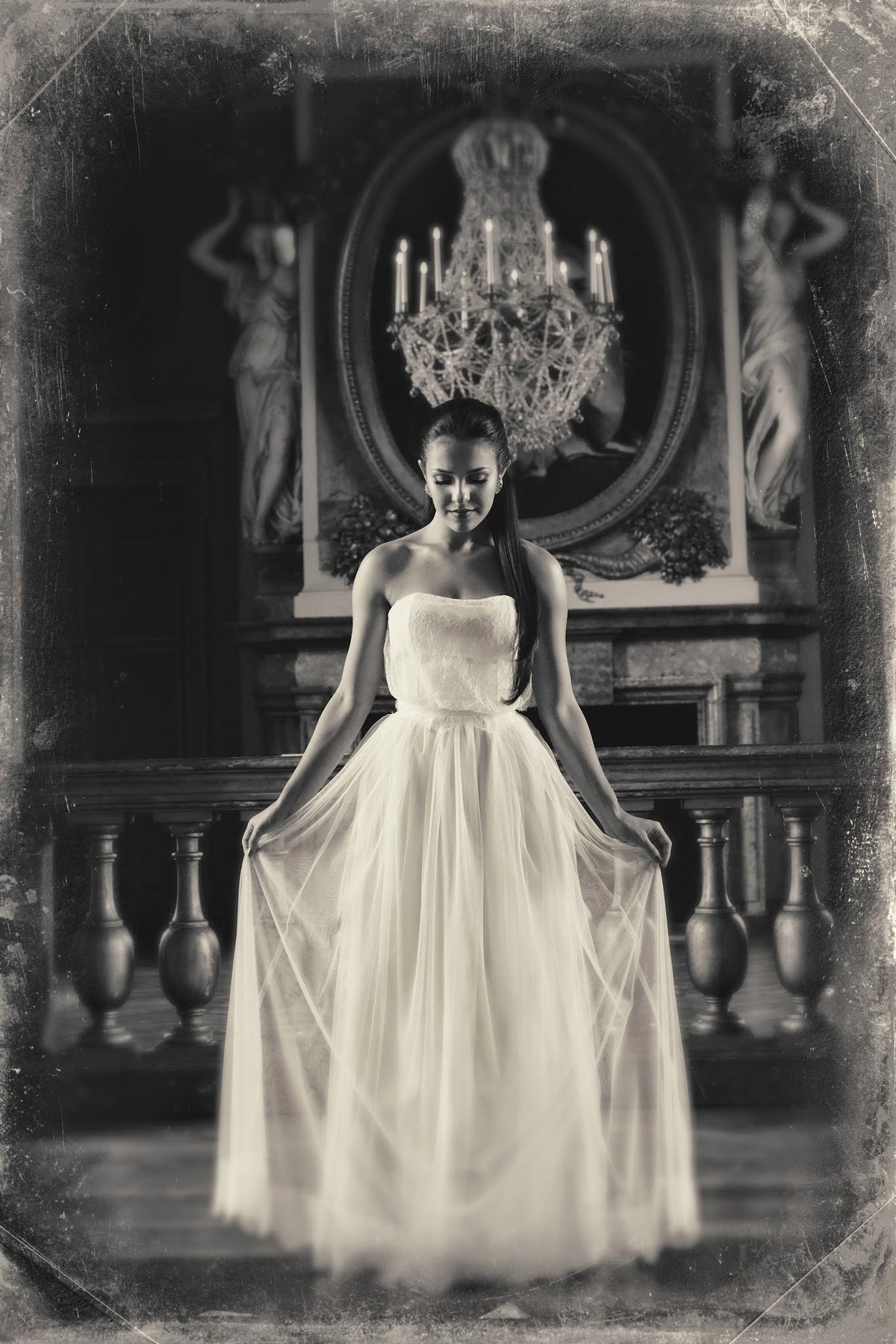 Bride posed beneath a chandelier in a black-and-white portrait