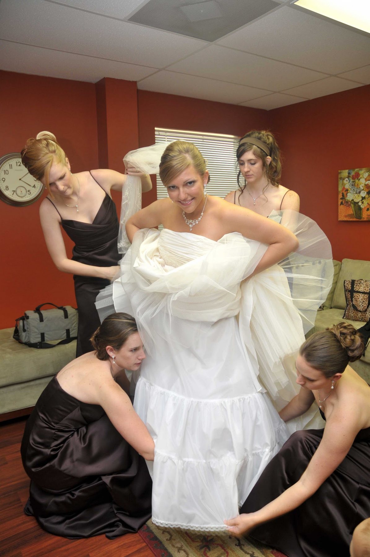 Bridesmaids helping a bride into her gown