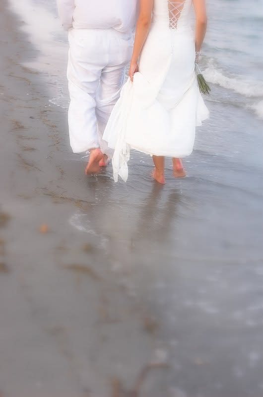 Newlyweds walking barefoot along the shoreline