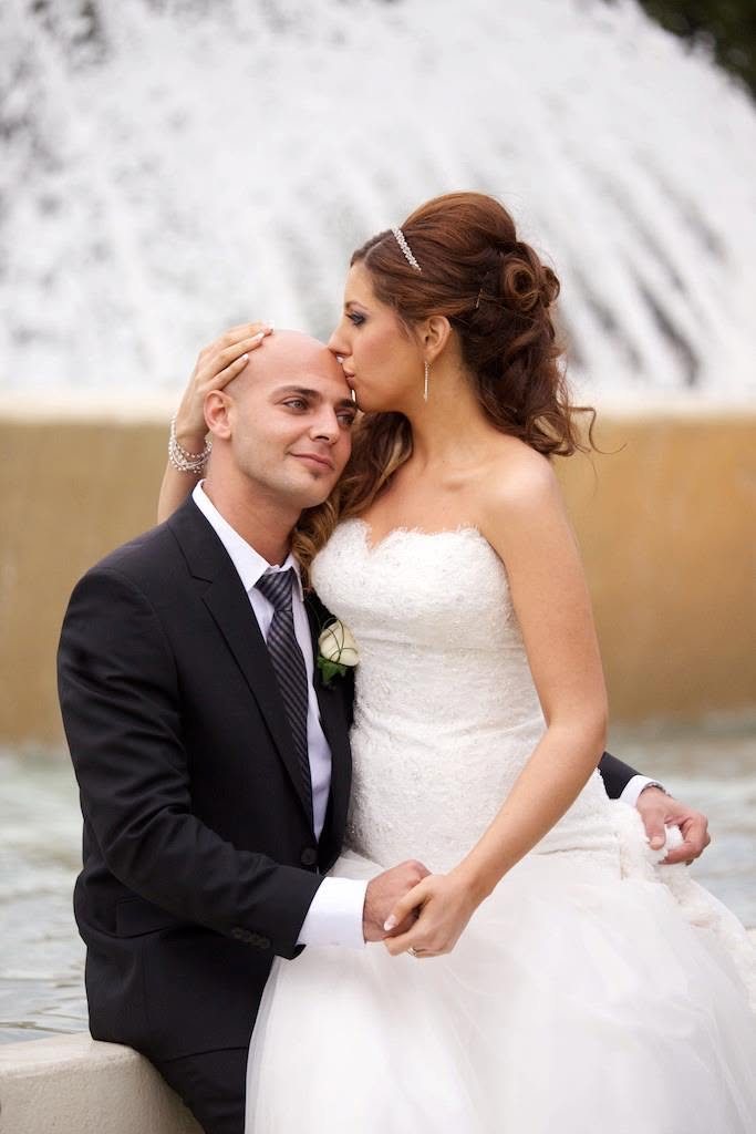 Bride kissing the groom beside a fountain