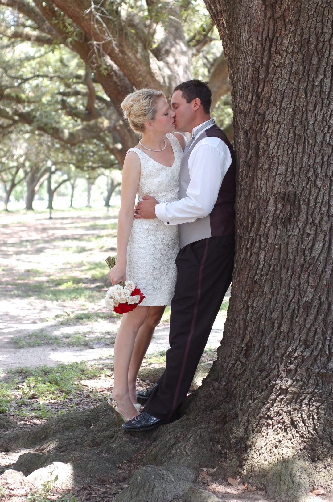 Newlyweds kissing beneath a large tree