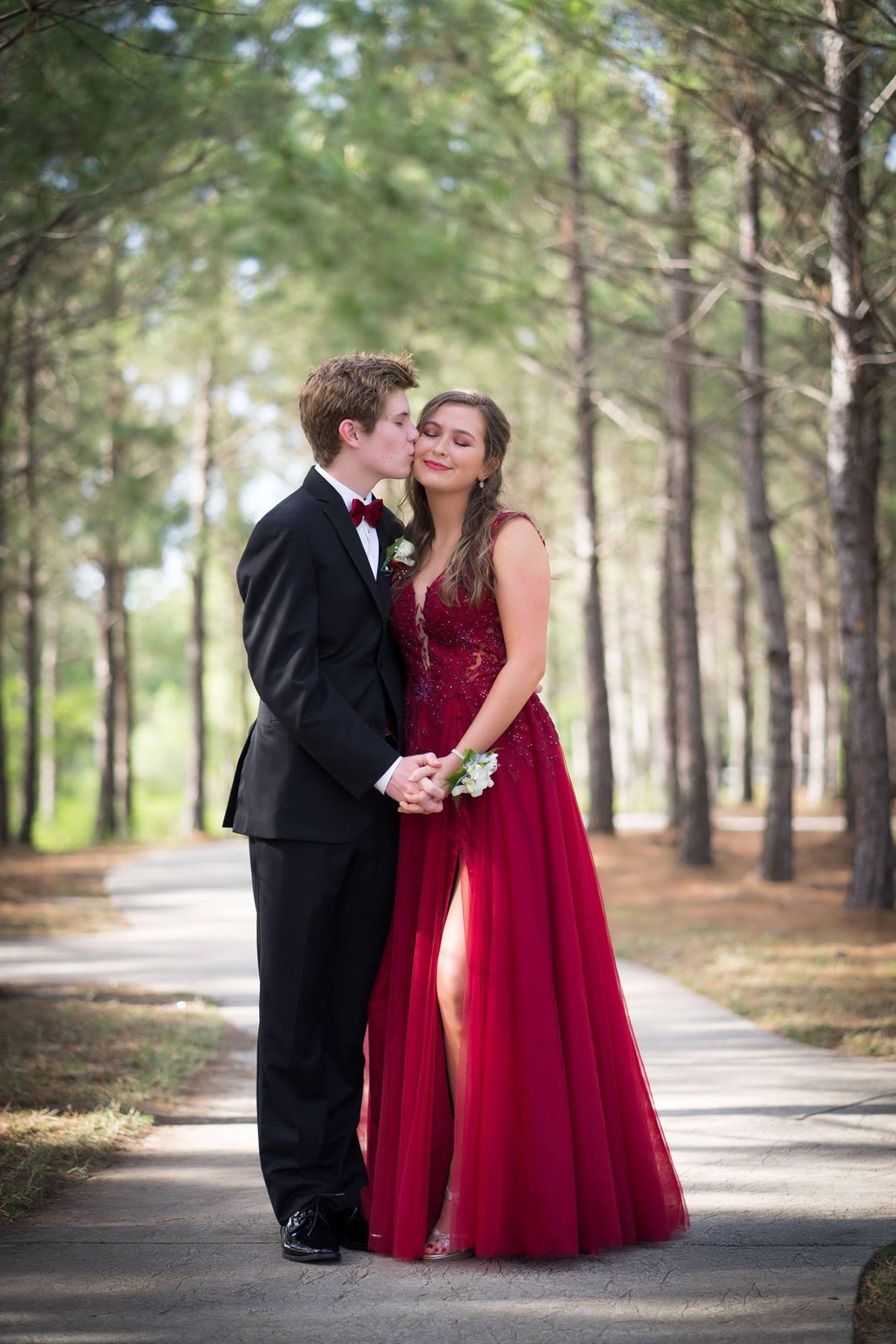 Young couple in formalwear standing in a wooded setting