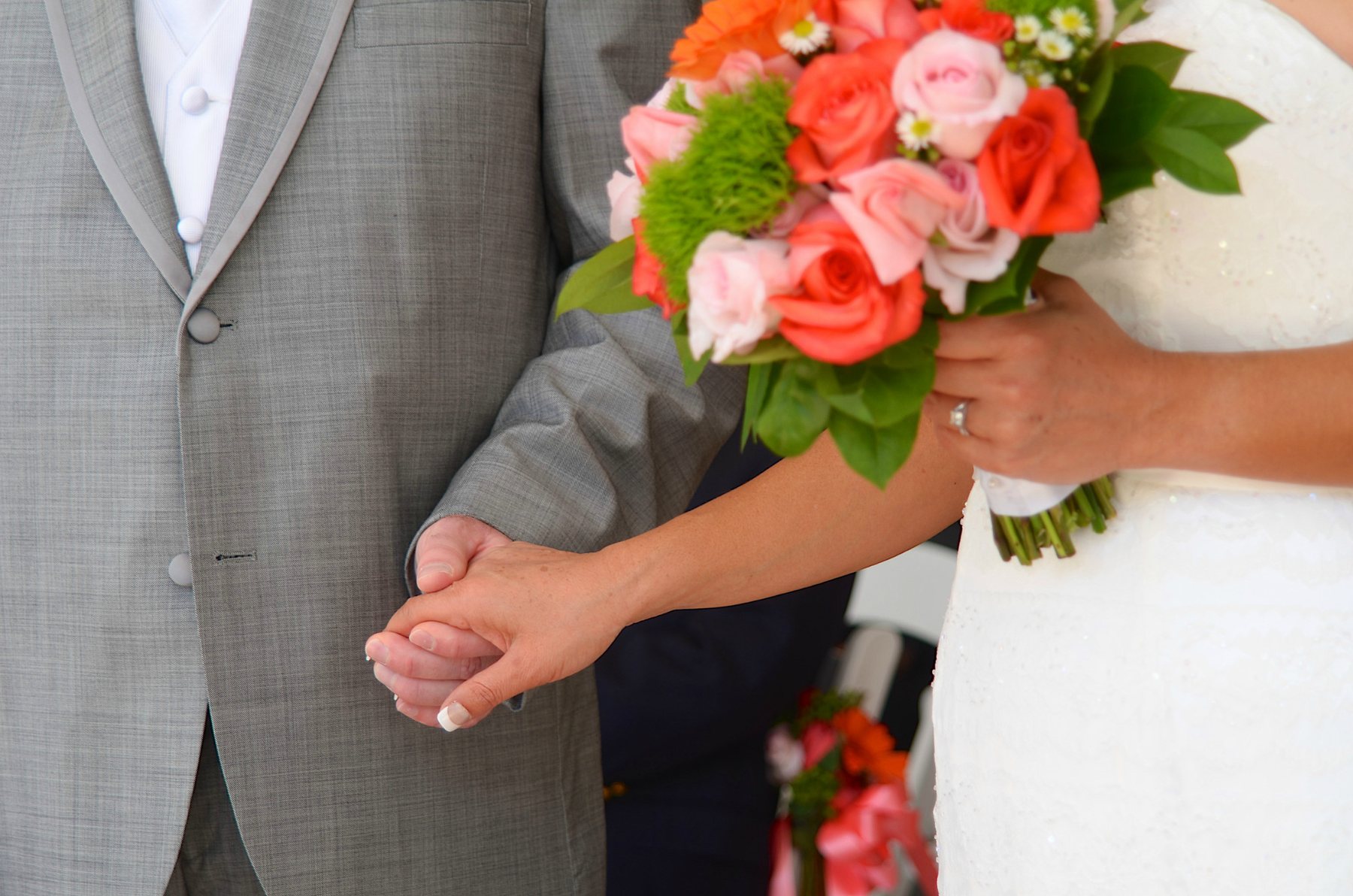 Newlyweds holding hands beside a colorful bouquet