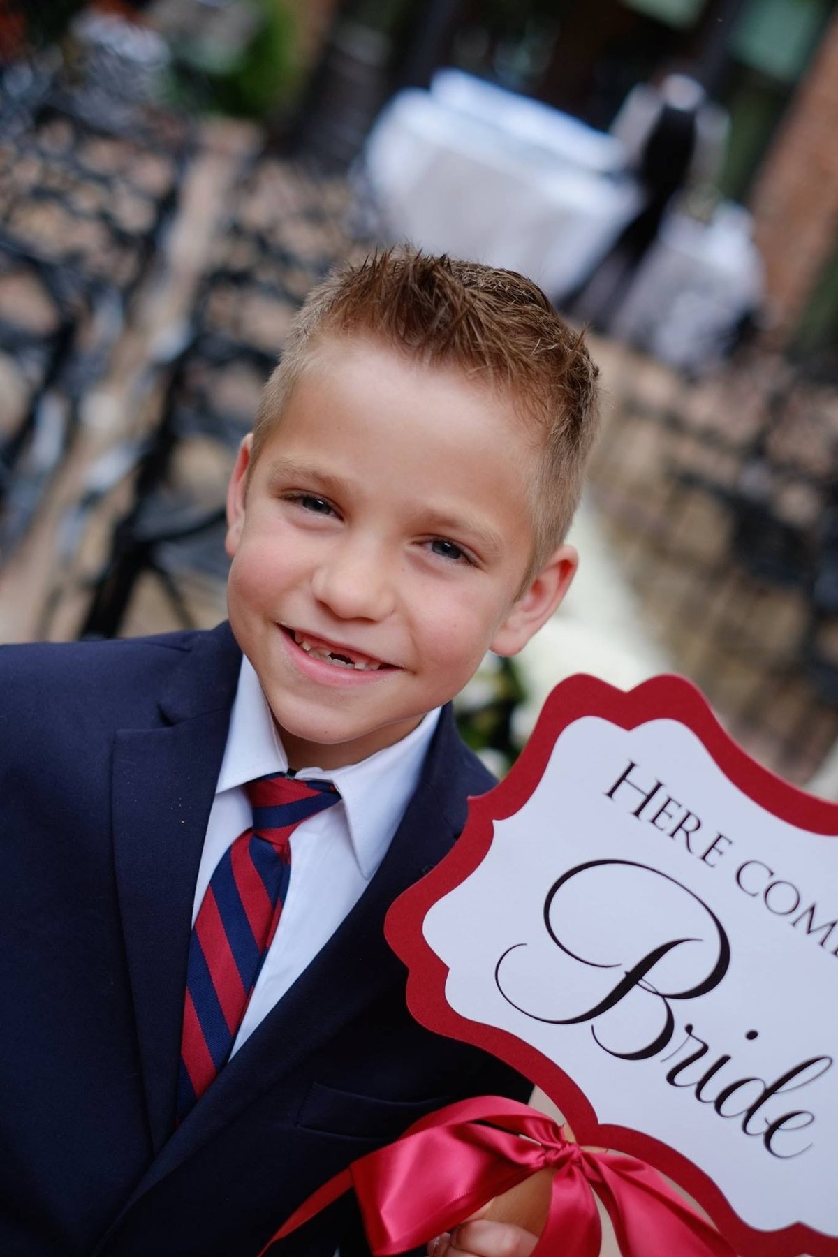 Young wedding attendant holding a Here Comes the Bride sign